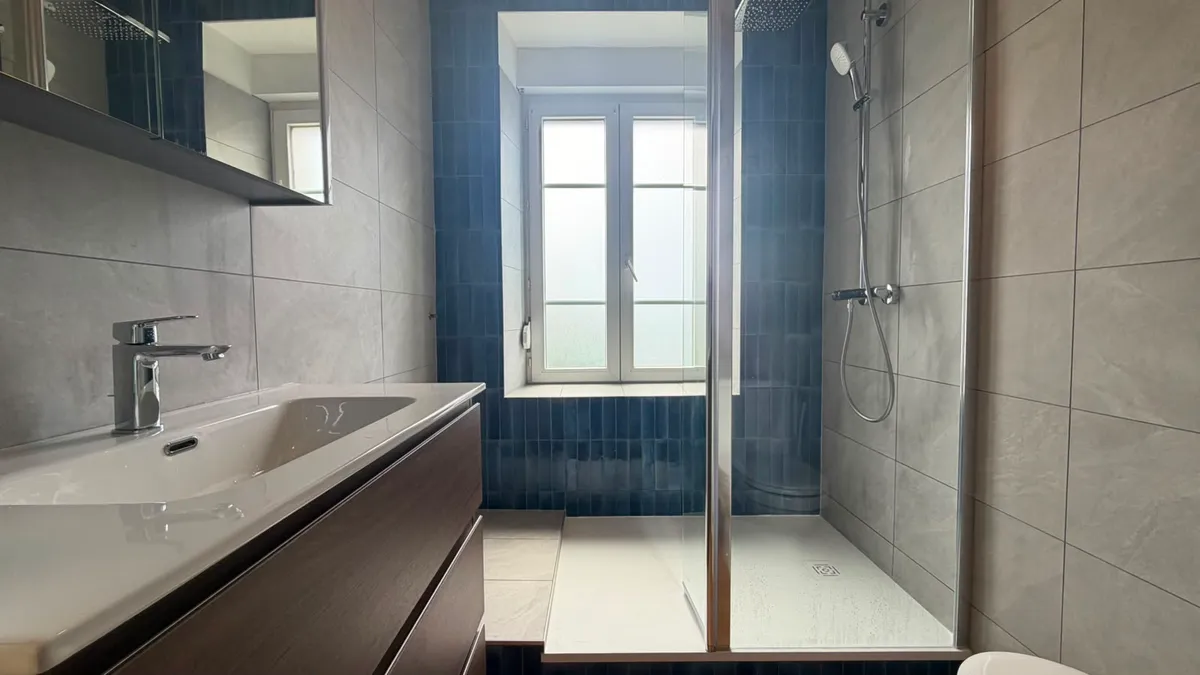 Rénovation de salle de bain avec douche à l'italienne, faïence bleue posée verticalement et meuble vasque suspendu en bois
