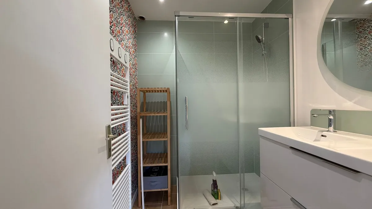 Rénovation de salle de bain avec douche à l'italienne moderne, faïence vert pastel, meuble vasque suspendu et papier peint végétal